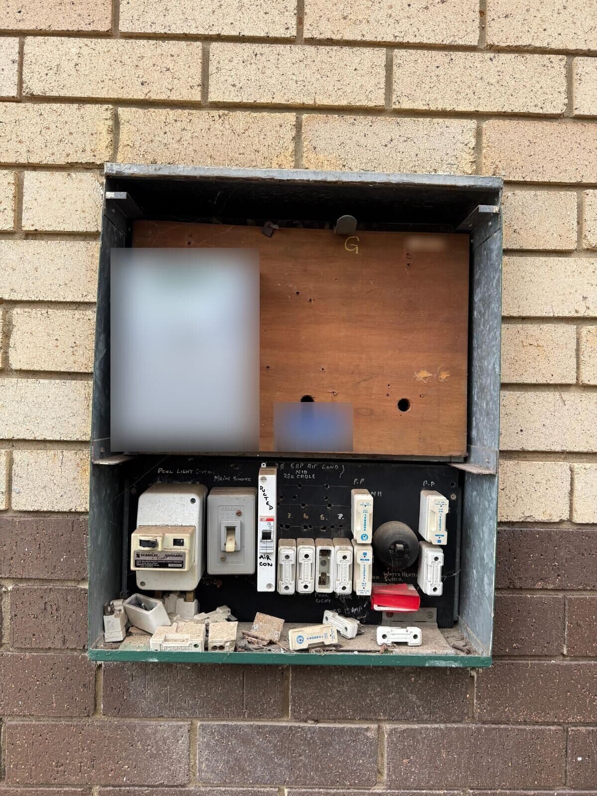 Old switchboard in a meter box, with rewireable fuses on a timber backing board