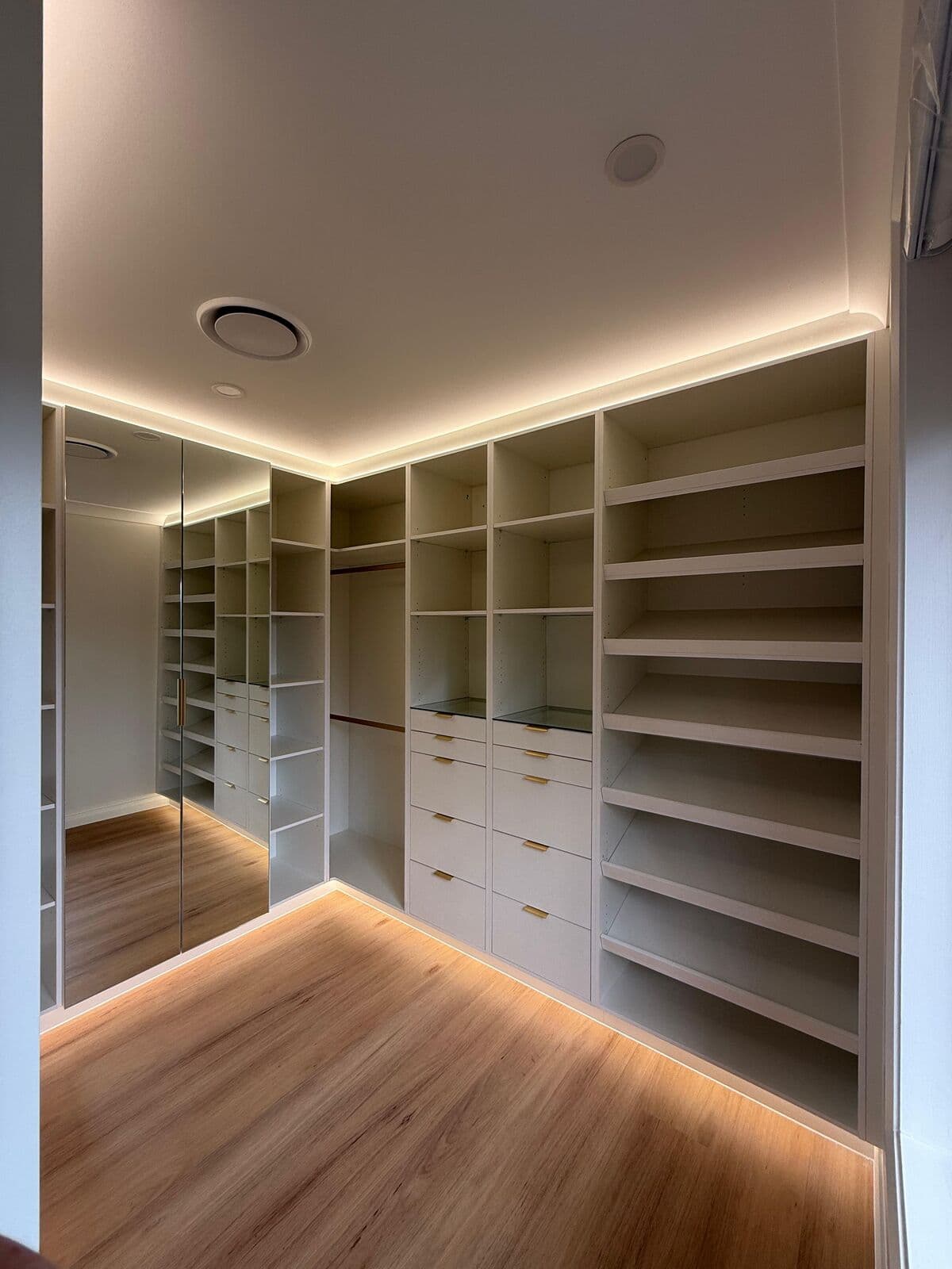 Walk-in wardrobe with illuminated ceiling perimeter and shelving base