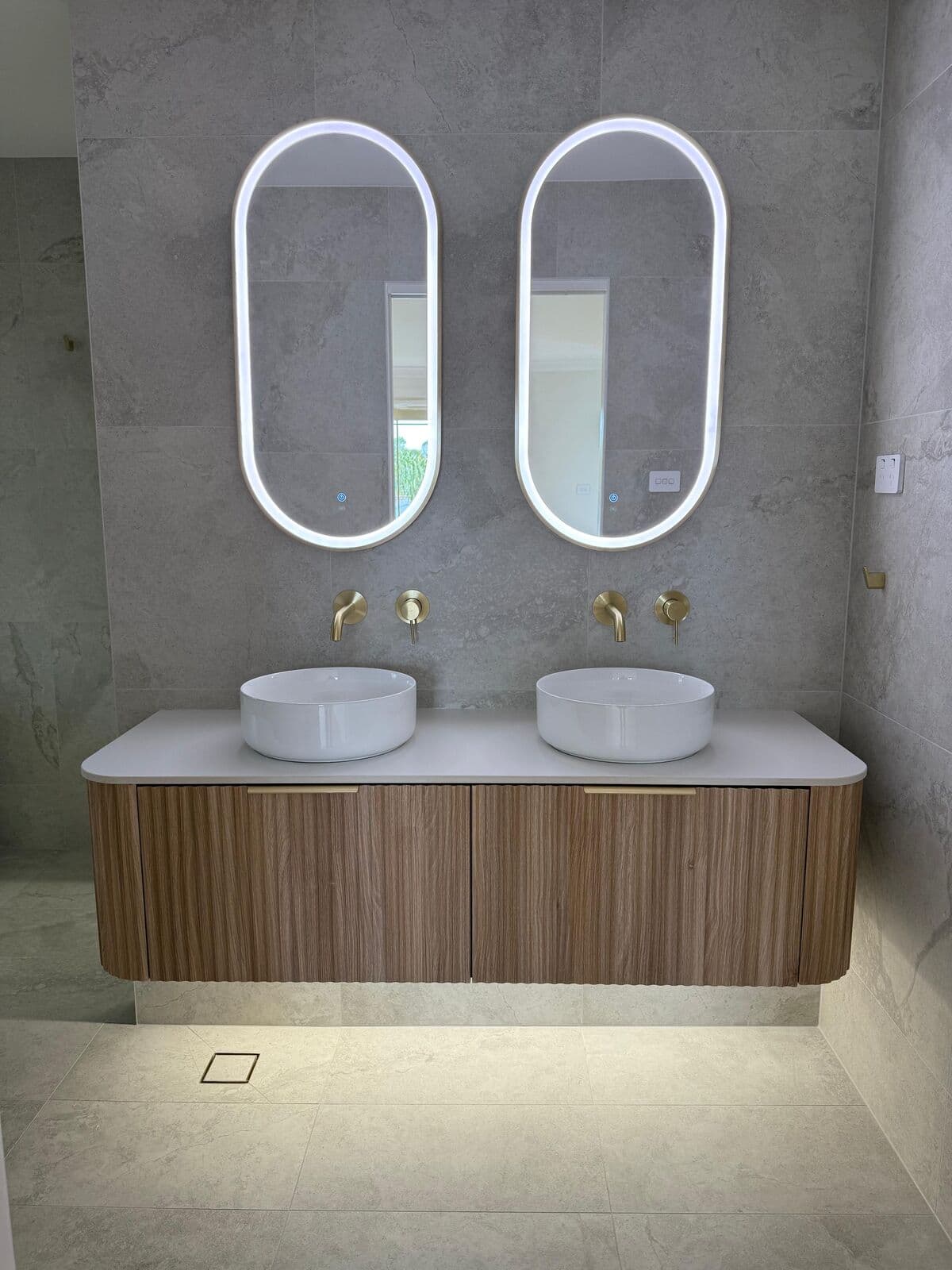 Double bathroom vanity with two illuminated oval mirrors