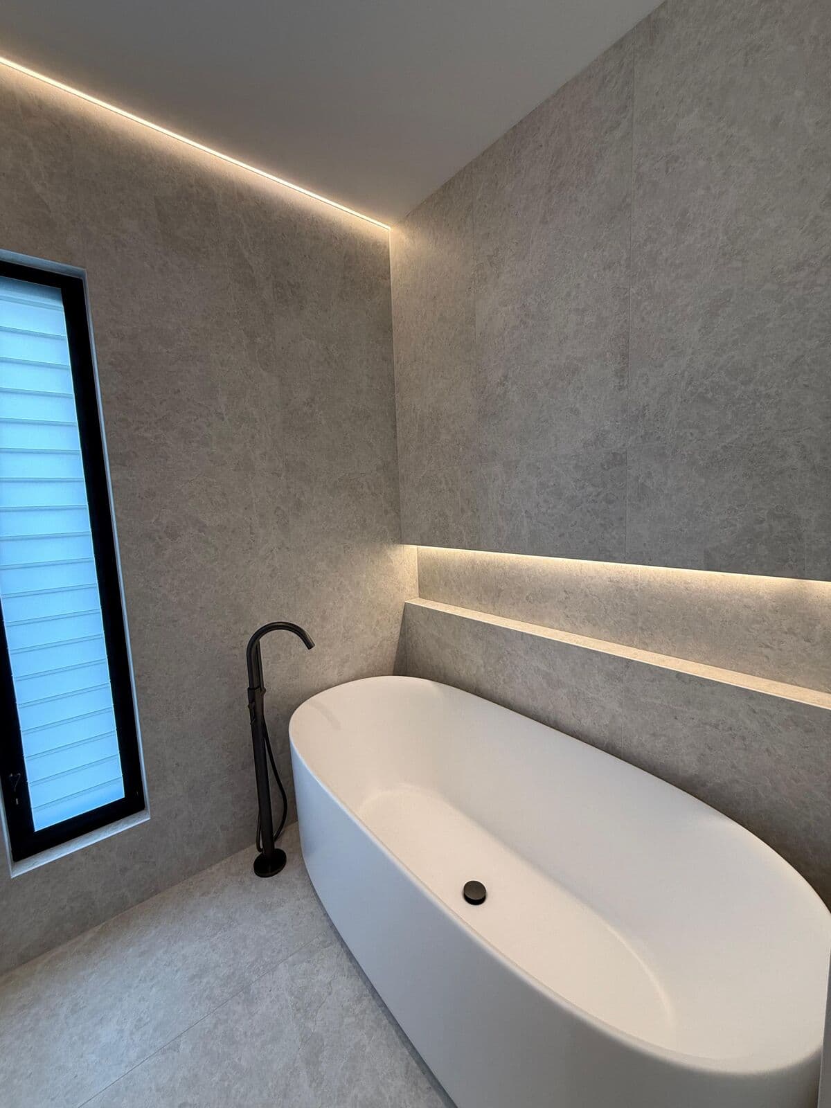 Freestanding bath below a lit ceiling recess
