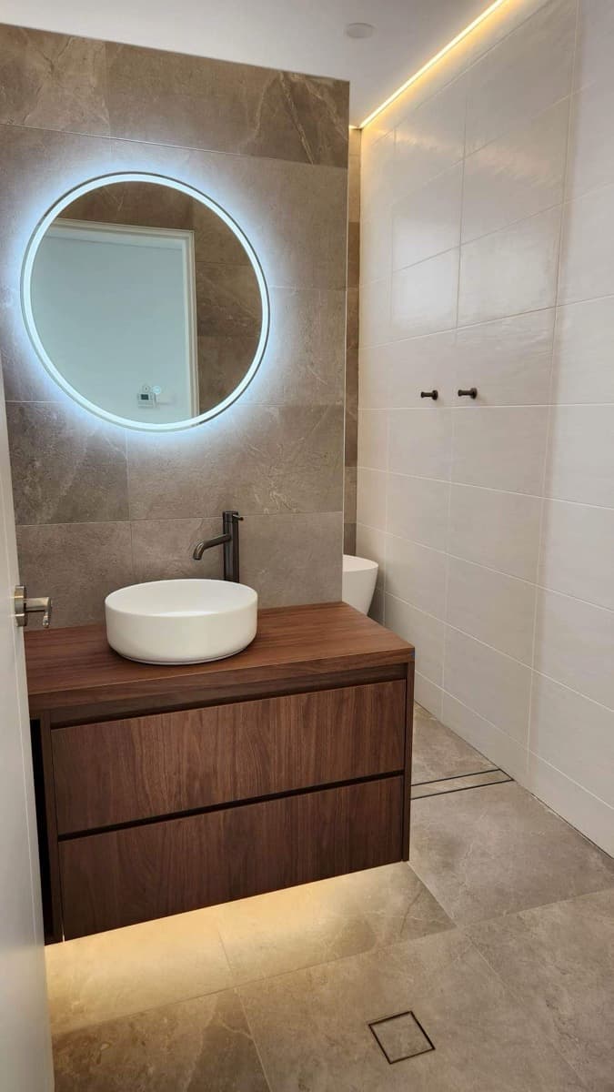 Round illuminated mirror above a bathroom basin