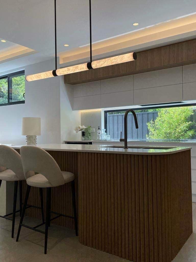 Kitchen island with a linear pendant and illuminated cabinetry