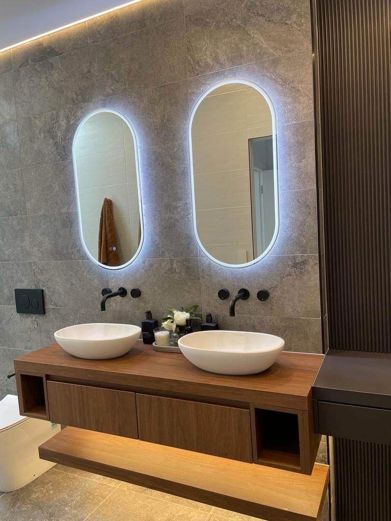 Double vanity with illuminated mirrors and lighting below cabinetry