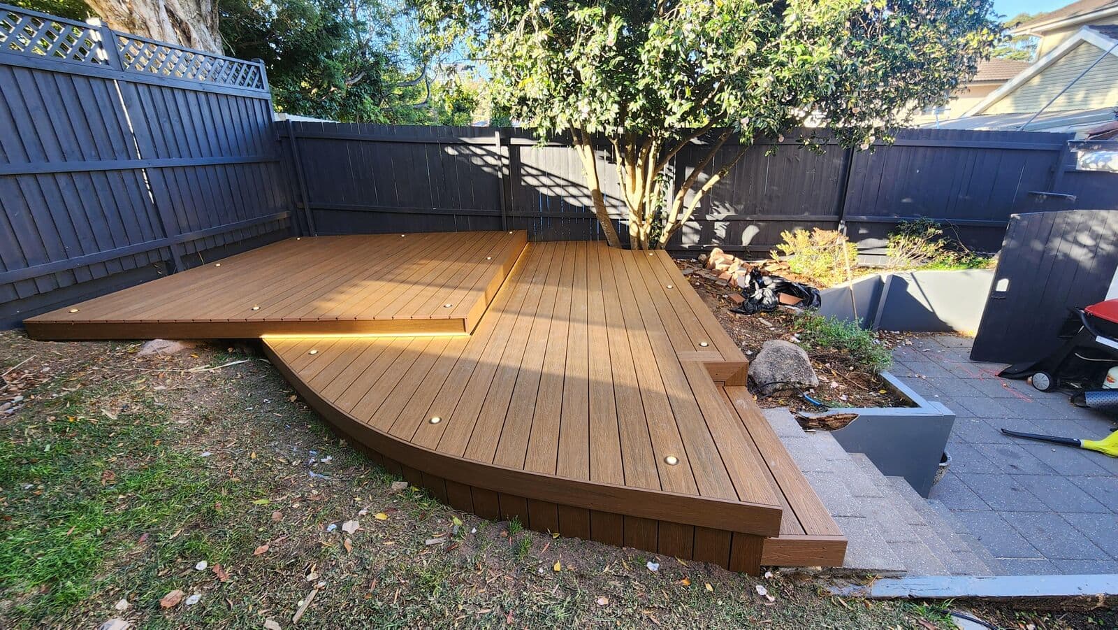 Timber garden deck with lights along its steps and surrounding planting