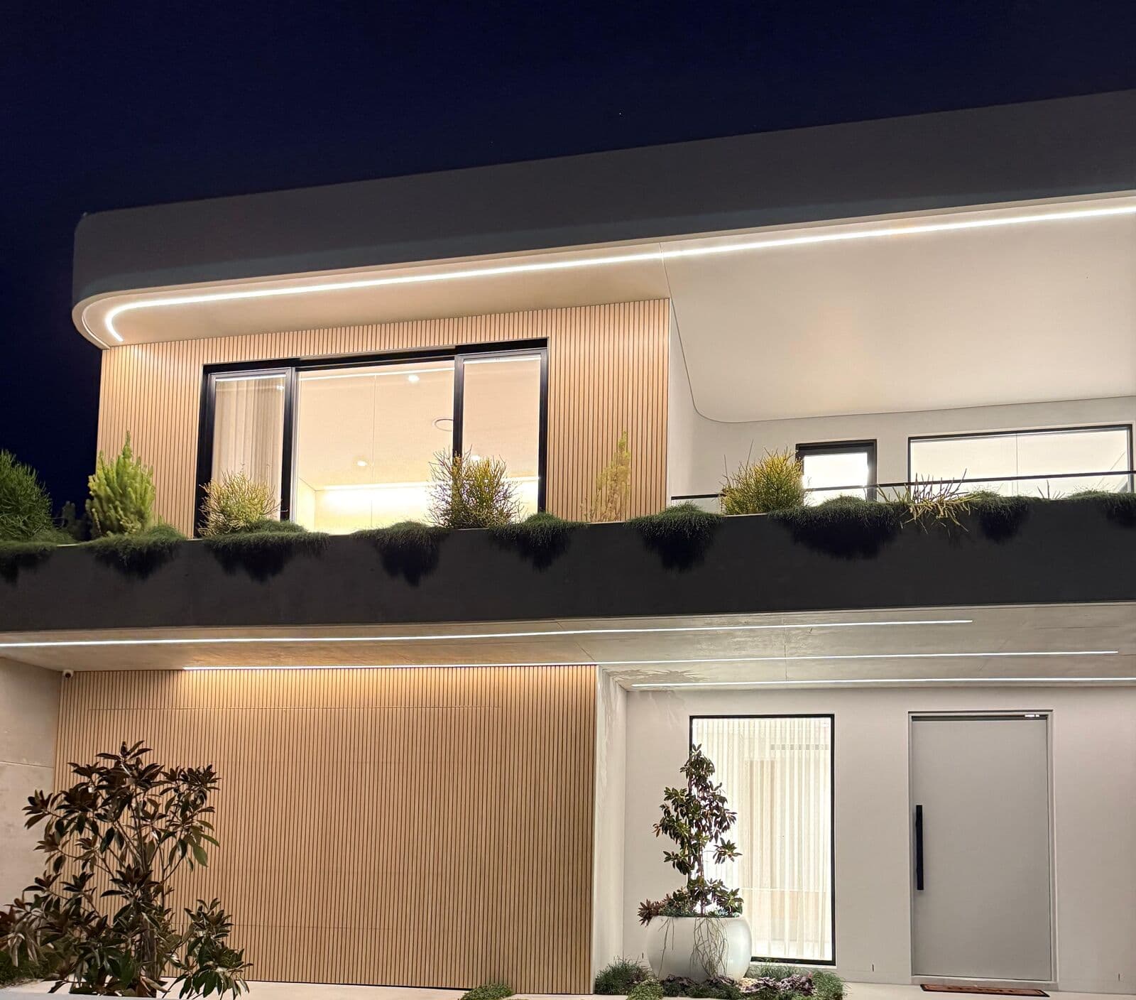 Two-storey home exterior with illuminated balcony and entry