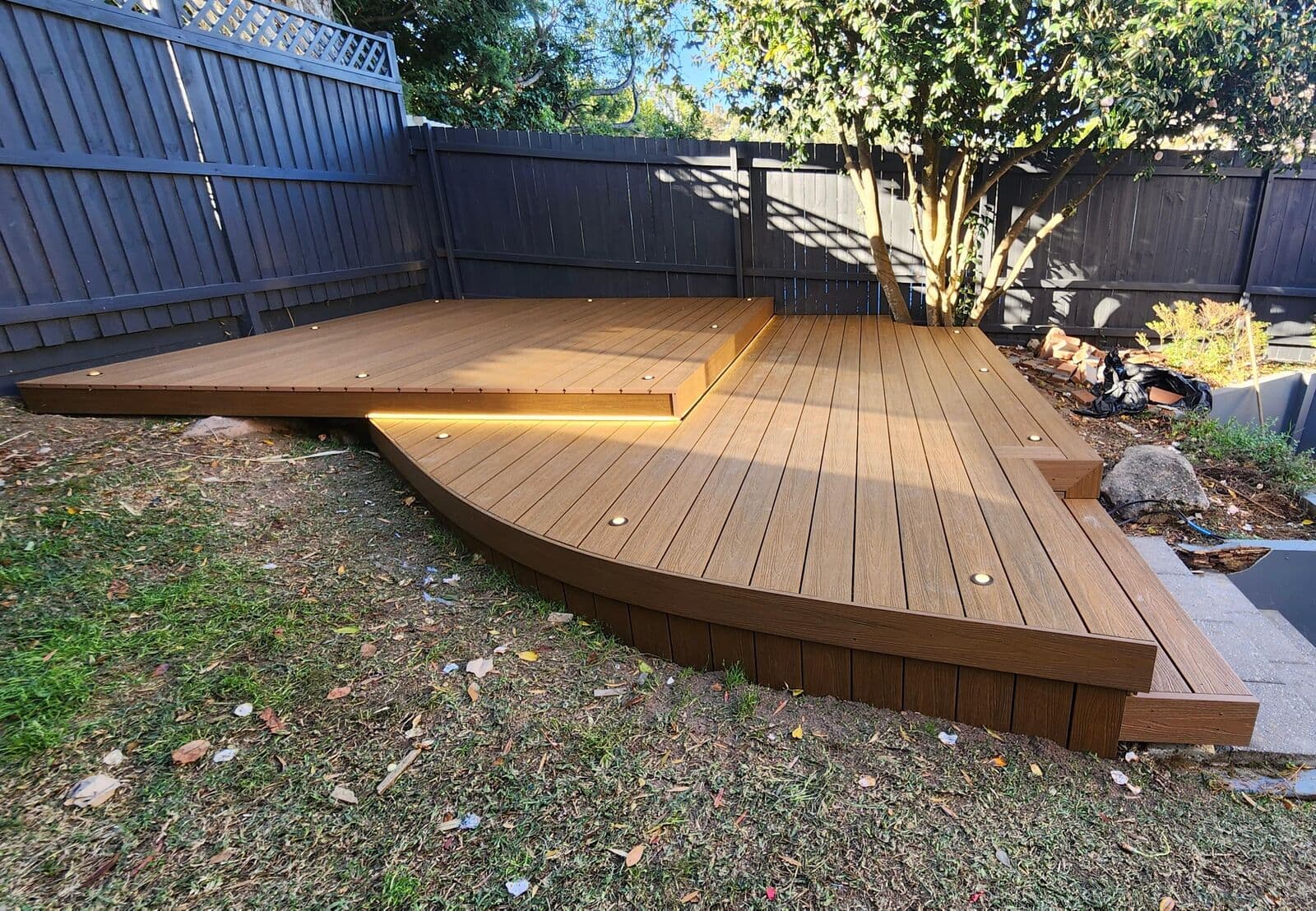 Timber garden deck with illuminated steps beside a tree