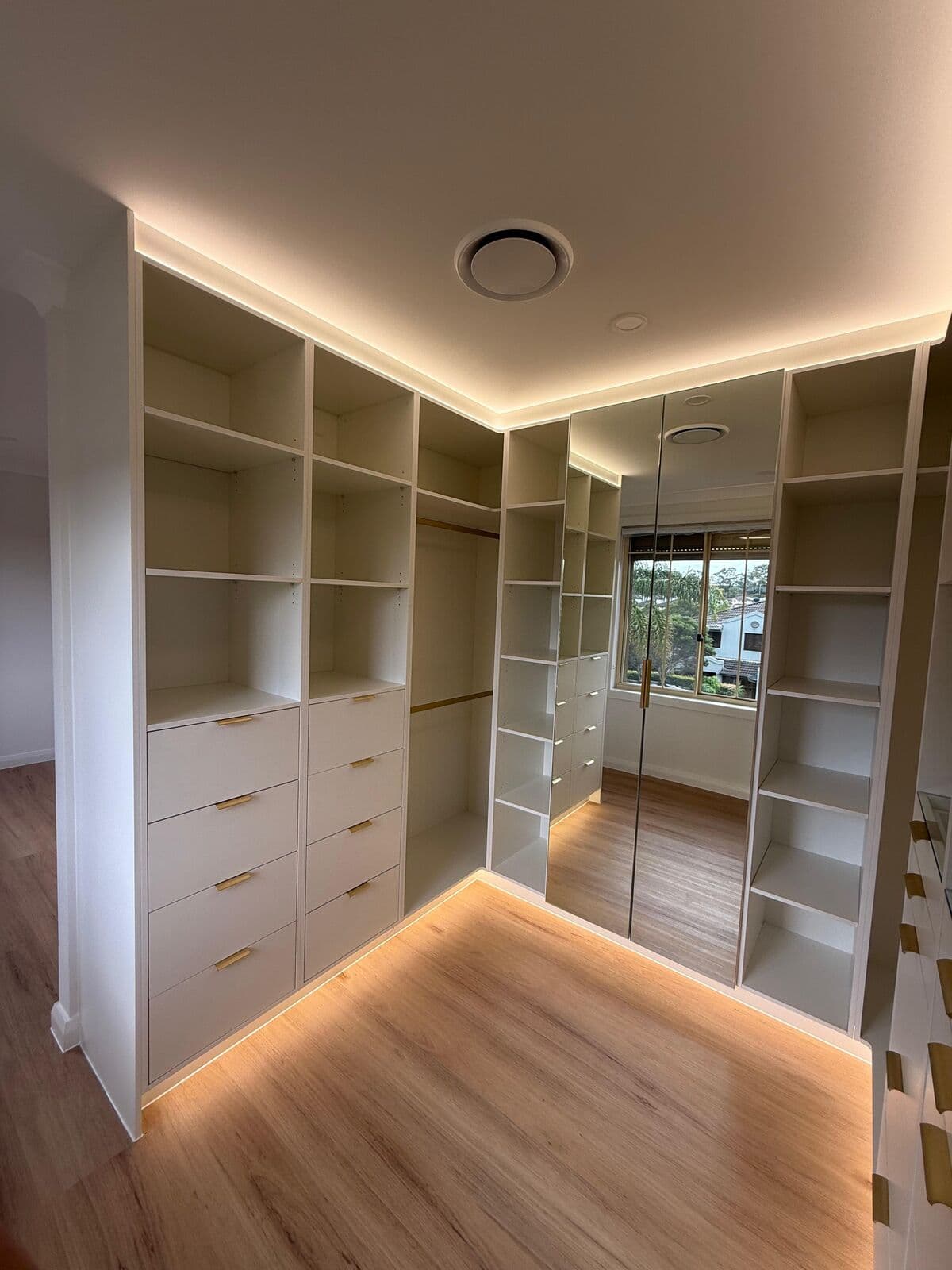 Walk-in wardrobe with lighting around the ceiling and joinery base