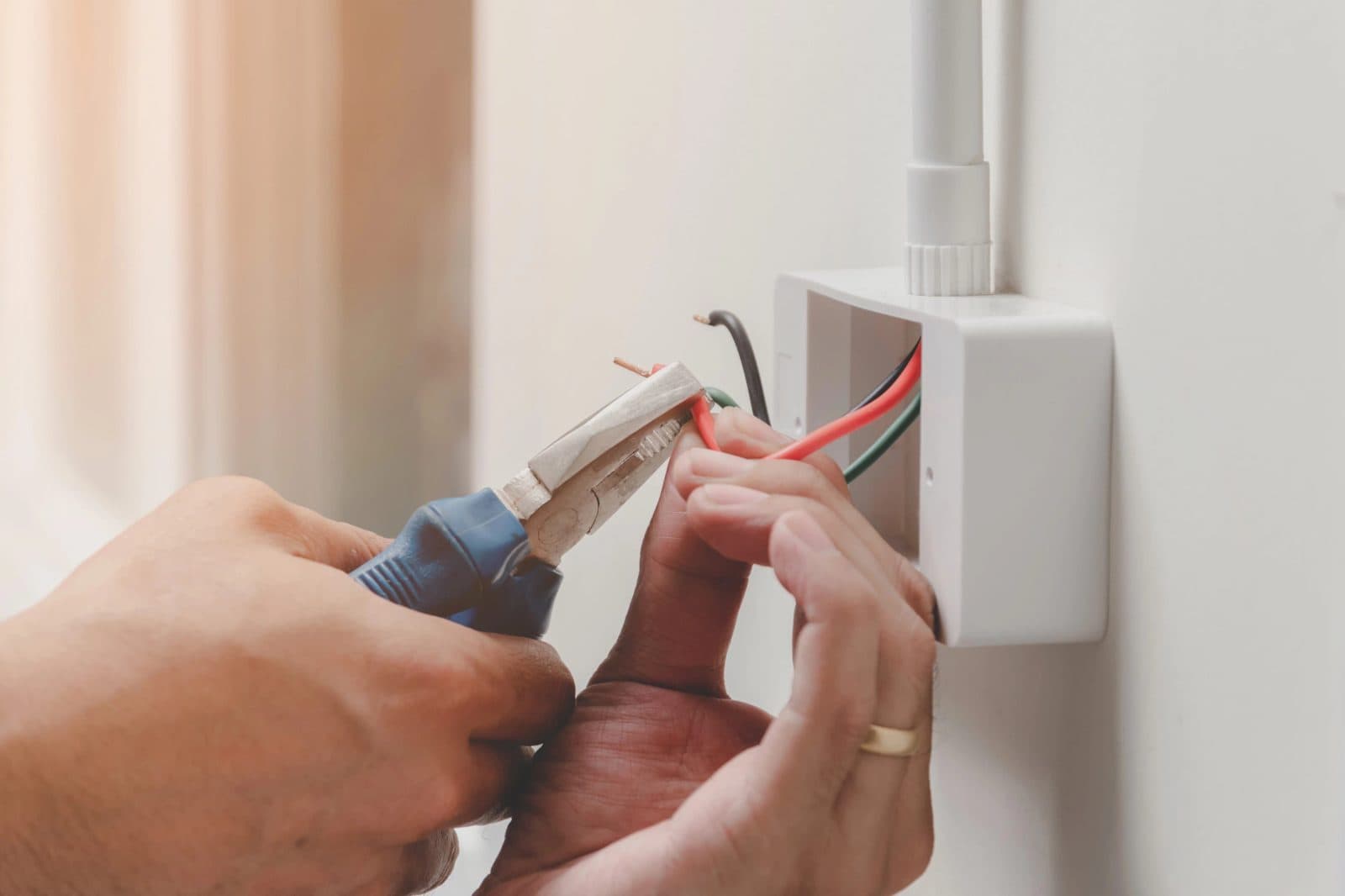 Electrician's hands connecting the wires of a wall power point