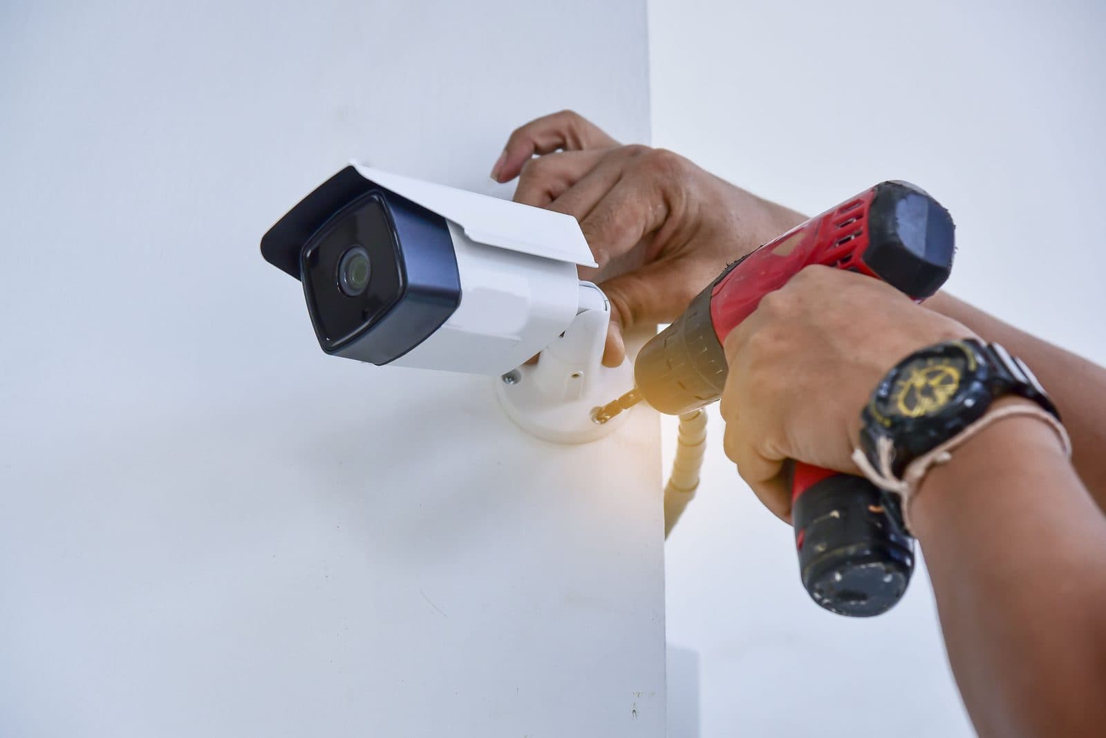 Security camera being fixed to an outside wall with a drill