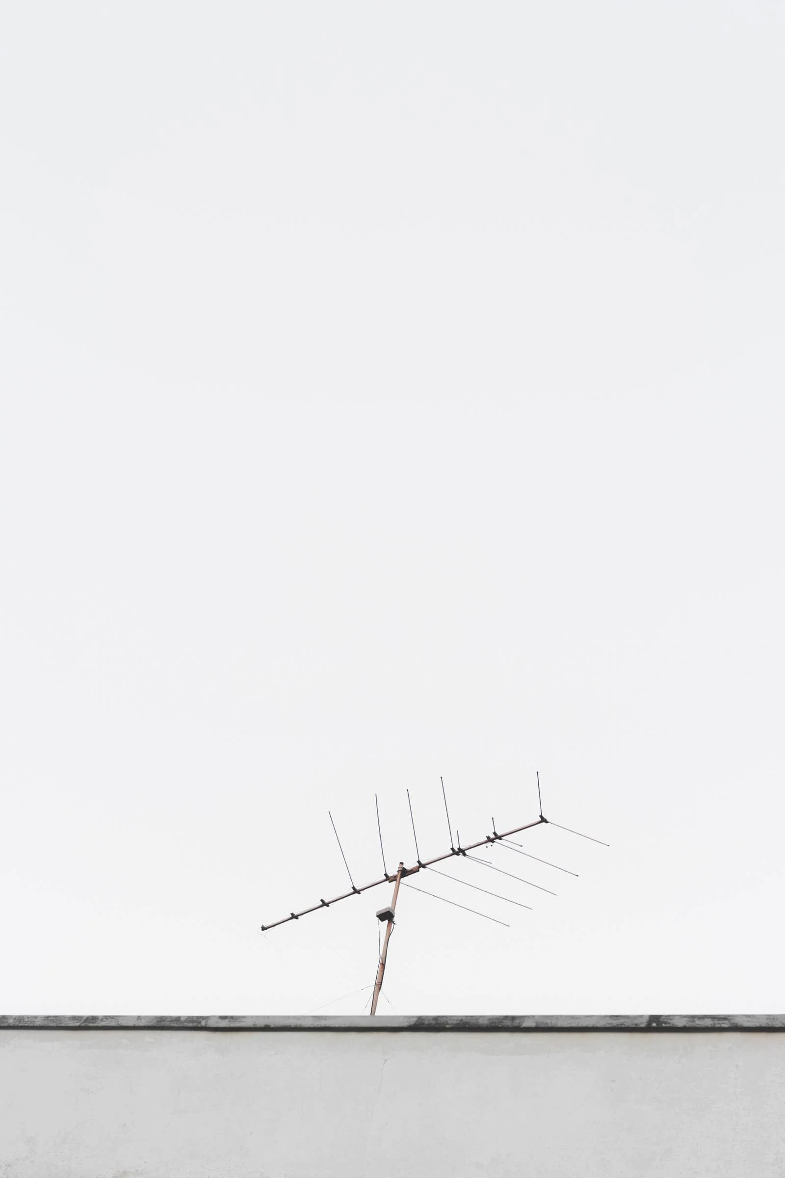 Rooftop television antenna against a pale grey sky